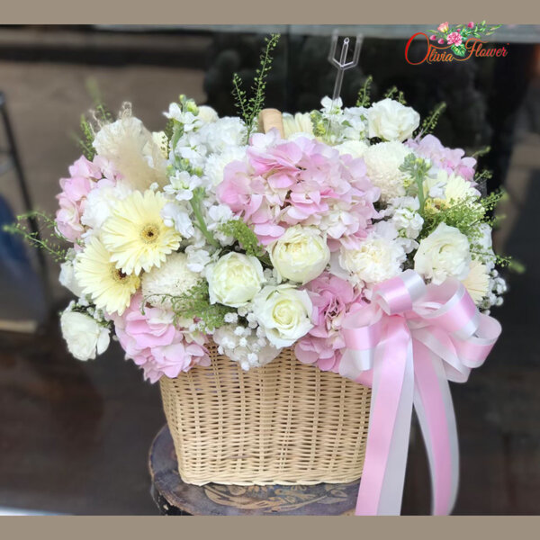กระเช้าดอกไม้สด ประกอบด้วย ไฮเดรนเยียสีชมพู กุหลาบสีขาว เยอบีร่า สต็อคสีขาว และไลเซนทรัสสีขาว